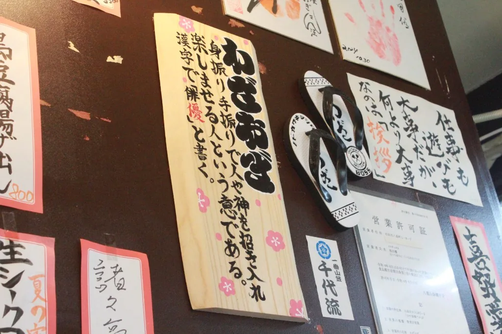 わざおぎの由来を書いた木の札。隣に草履が掛かっている